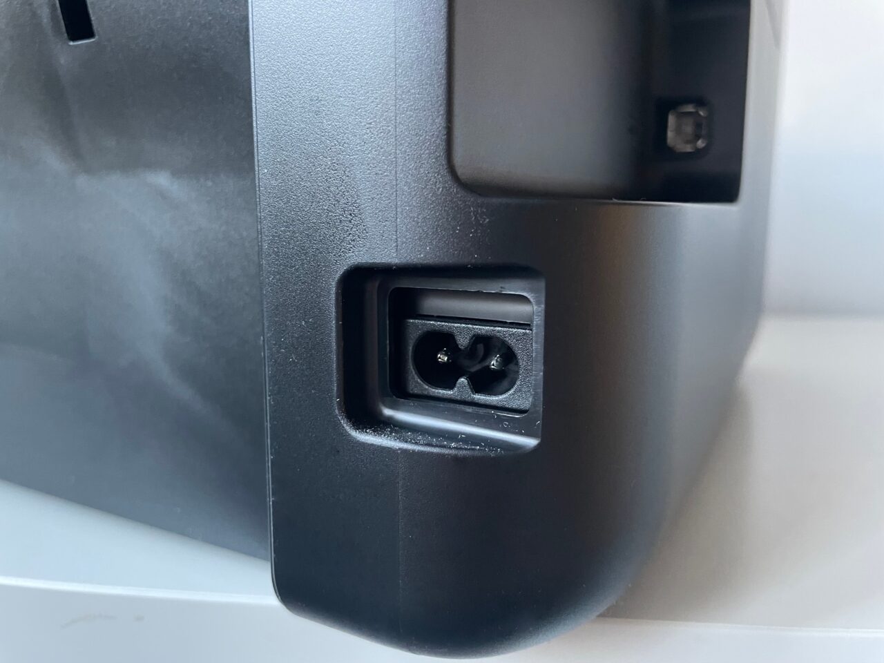 recenzja epson ecotank l3251. Zdjęcie tyłu urządzenia elektronicznego z widocznym portem zasilania typu trójząb oraz innym, mniejszym portem.