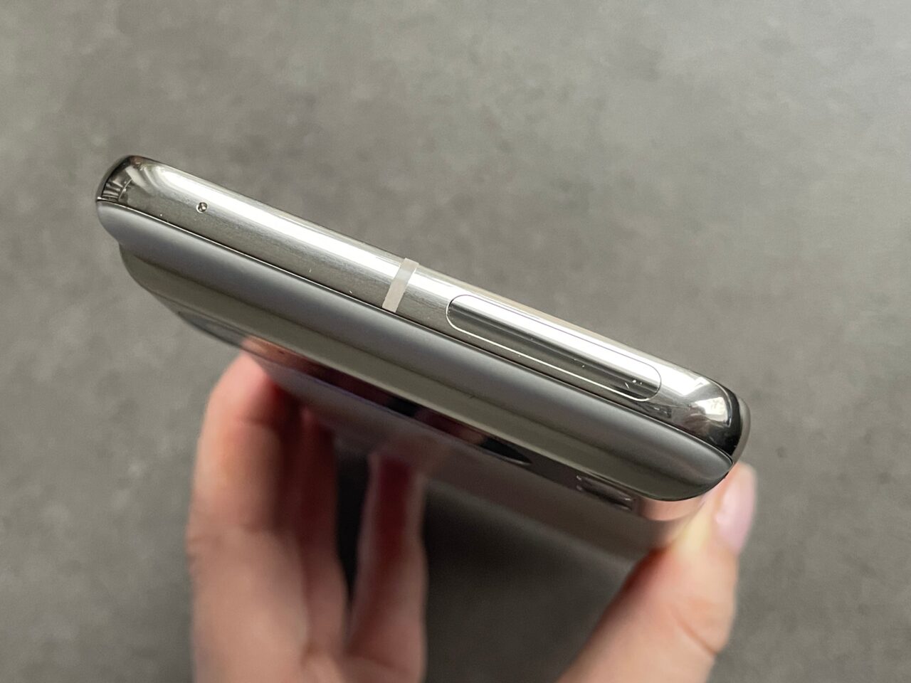 Zdjęcie zamkniętego srebrnego telefonu komórkowego trzymanego w dłoni.