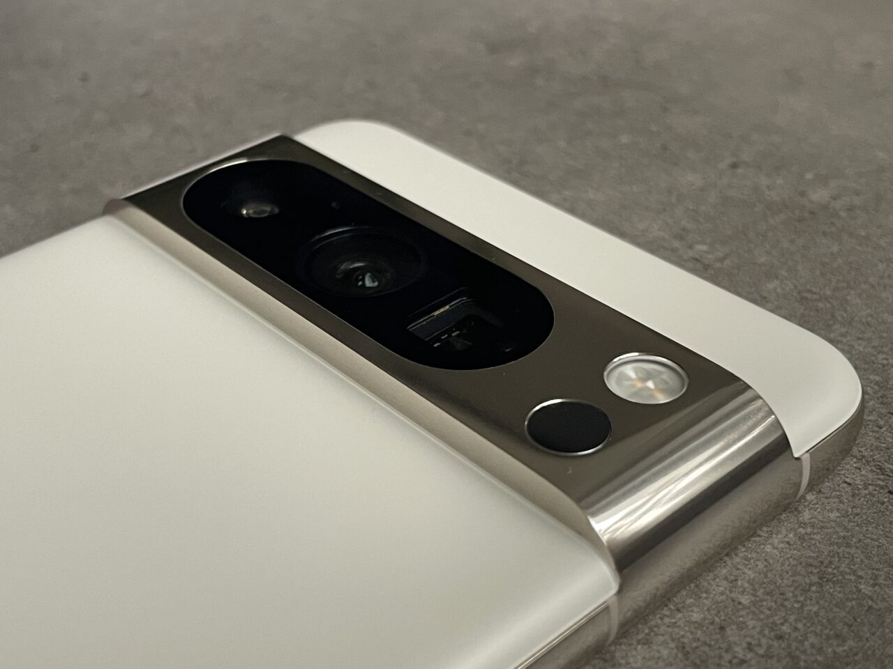 Aparat i błysk smartfona z podwójnym obiektywem umieszczony na metalowej krawędzi, z białą tylną obudową.