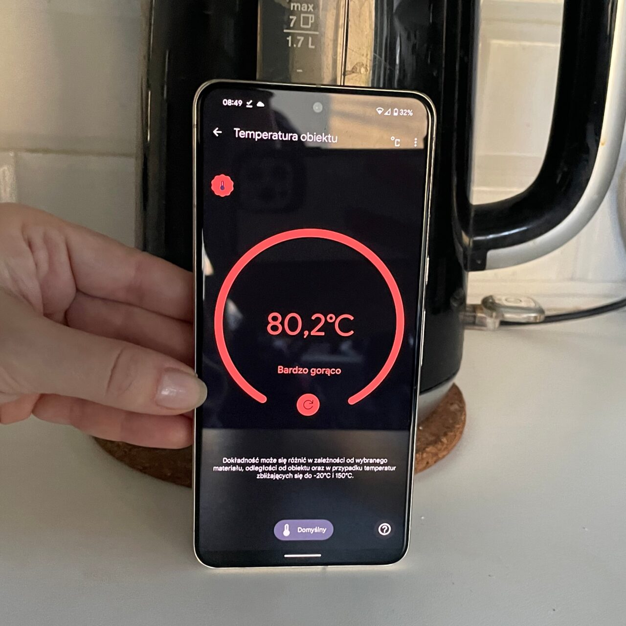 Ręka trzymająca smartfon, na ekranie aplikacja mierząca temperaturę pokazuje 80,2°C z opisem "Bardzo gorąco".