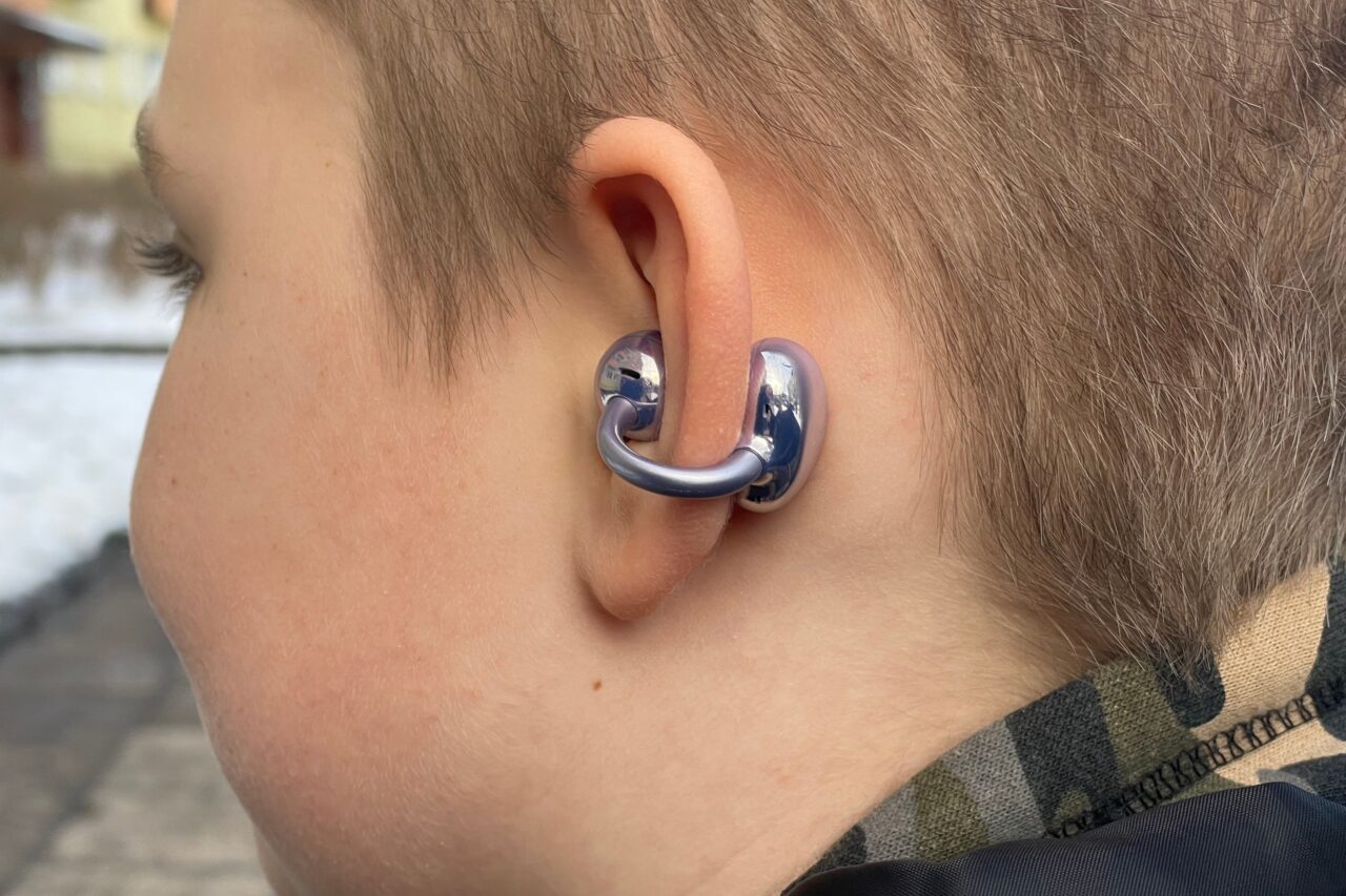 Ucho osoby noszącej metalowy, niebieski aparat słuchowy.