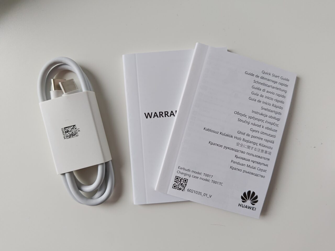 Biały kabel USB i instrukcje obsługi z gwarancją firmy Huawei na białym tle.