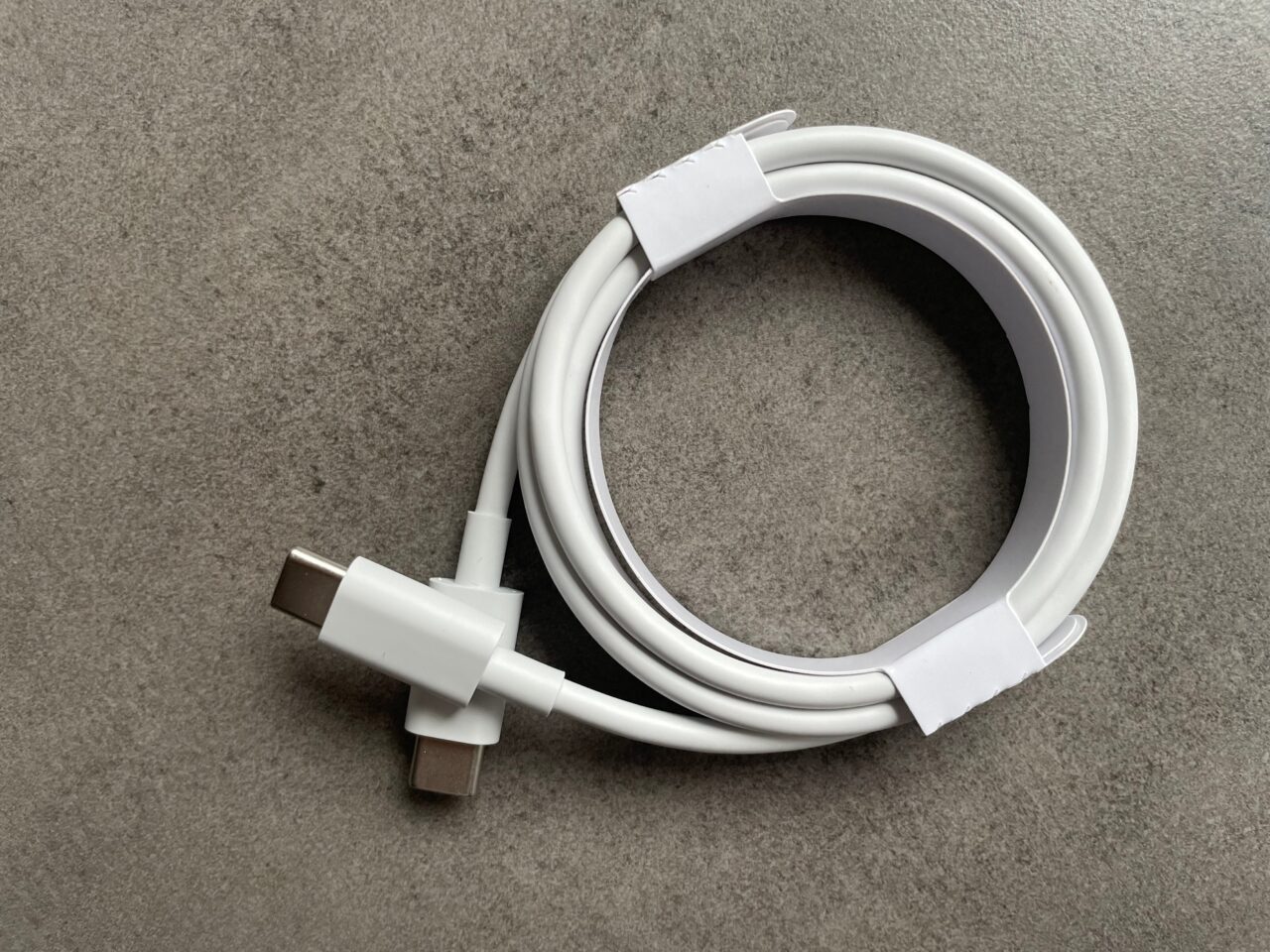 Biały kabel USB-C leżący na szarym tle.