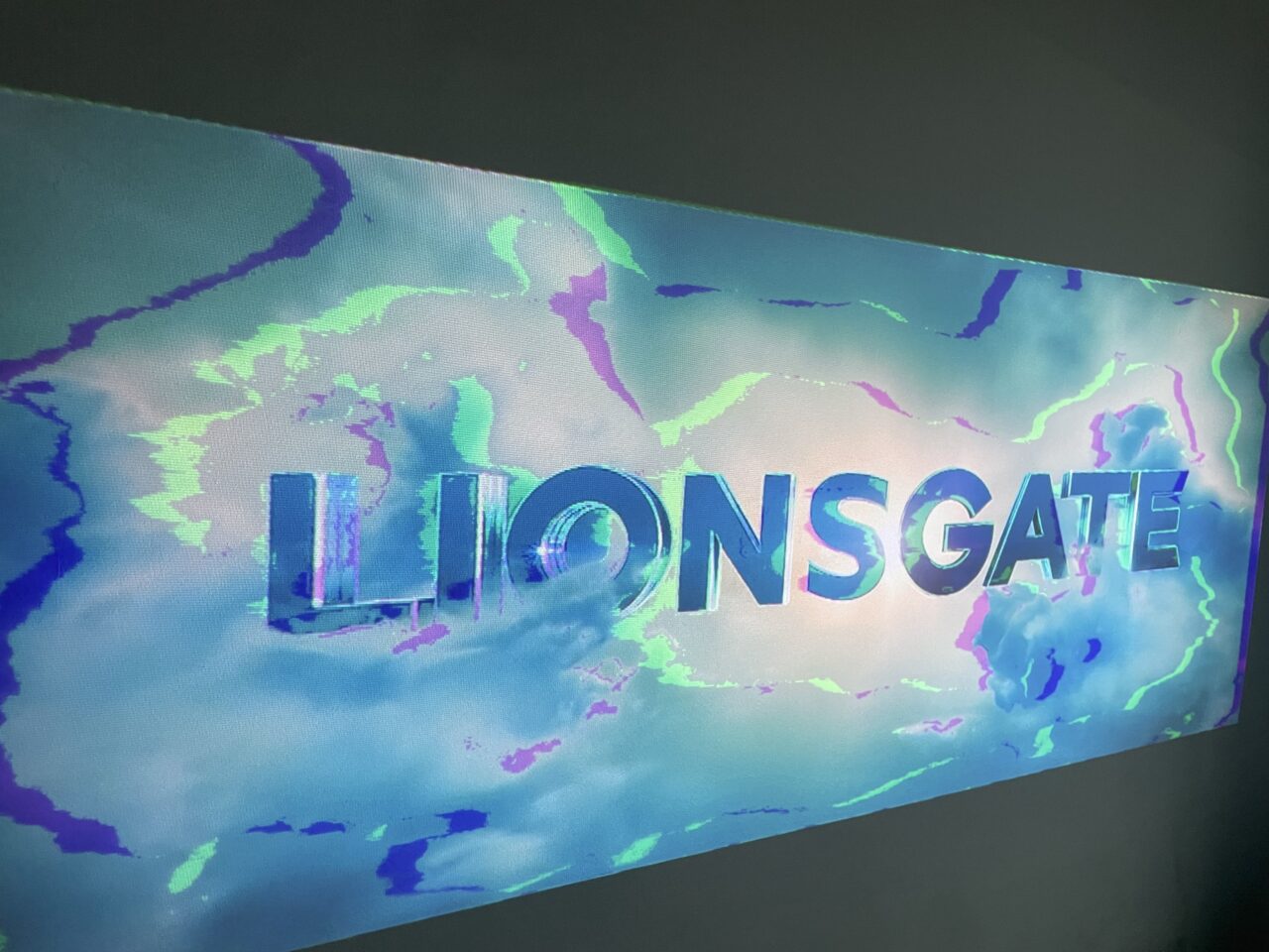 Logo Lionsgate z holograficznym efektem kolorystycznym na ścianie.