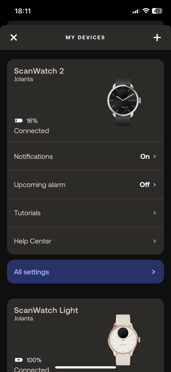 Ekran aplikacji mobilnej pokazujący zarządzanie dwoma połączonymi urządzeniami: ScanWatch 2 i ScanWatch Light z nazwą użytkownika "Jolanta". Pokazuje stan baterii oraz opcje takie jak połączenie, powiadomienia i alarm.
