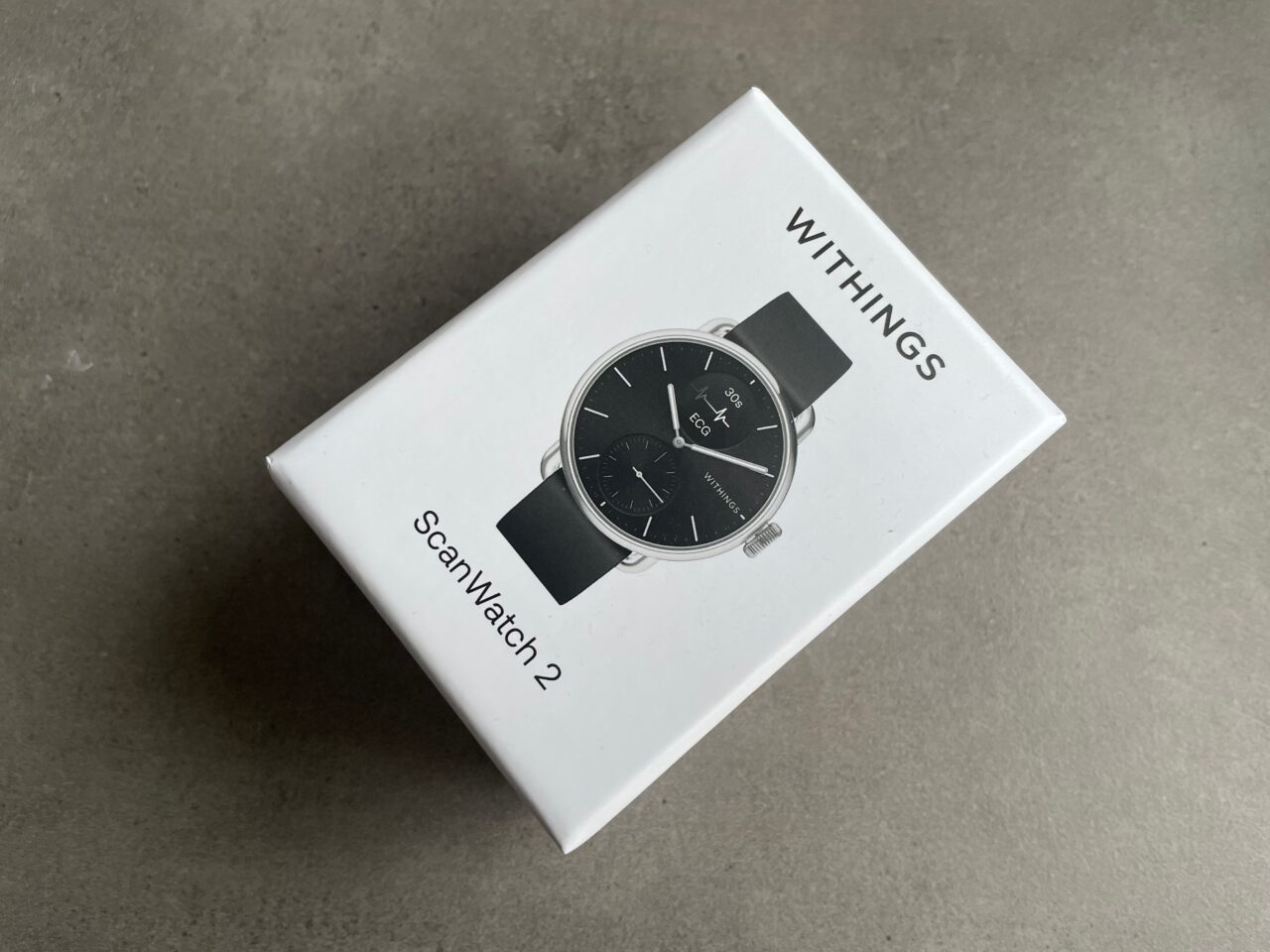 Opakowanie zegarka Withings ScanWatch 2 na szarym tle.