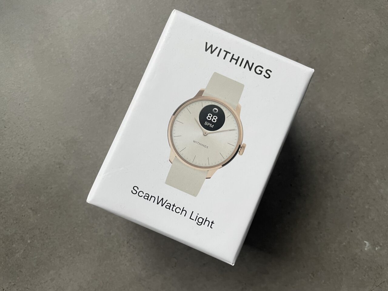 Opakowanie zegarka Withings ScanWatch Light w kolorze białym z wizerunkiem zegarka na wierzchu.