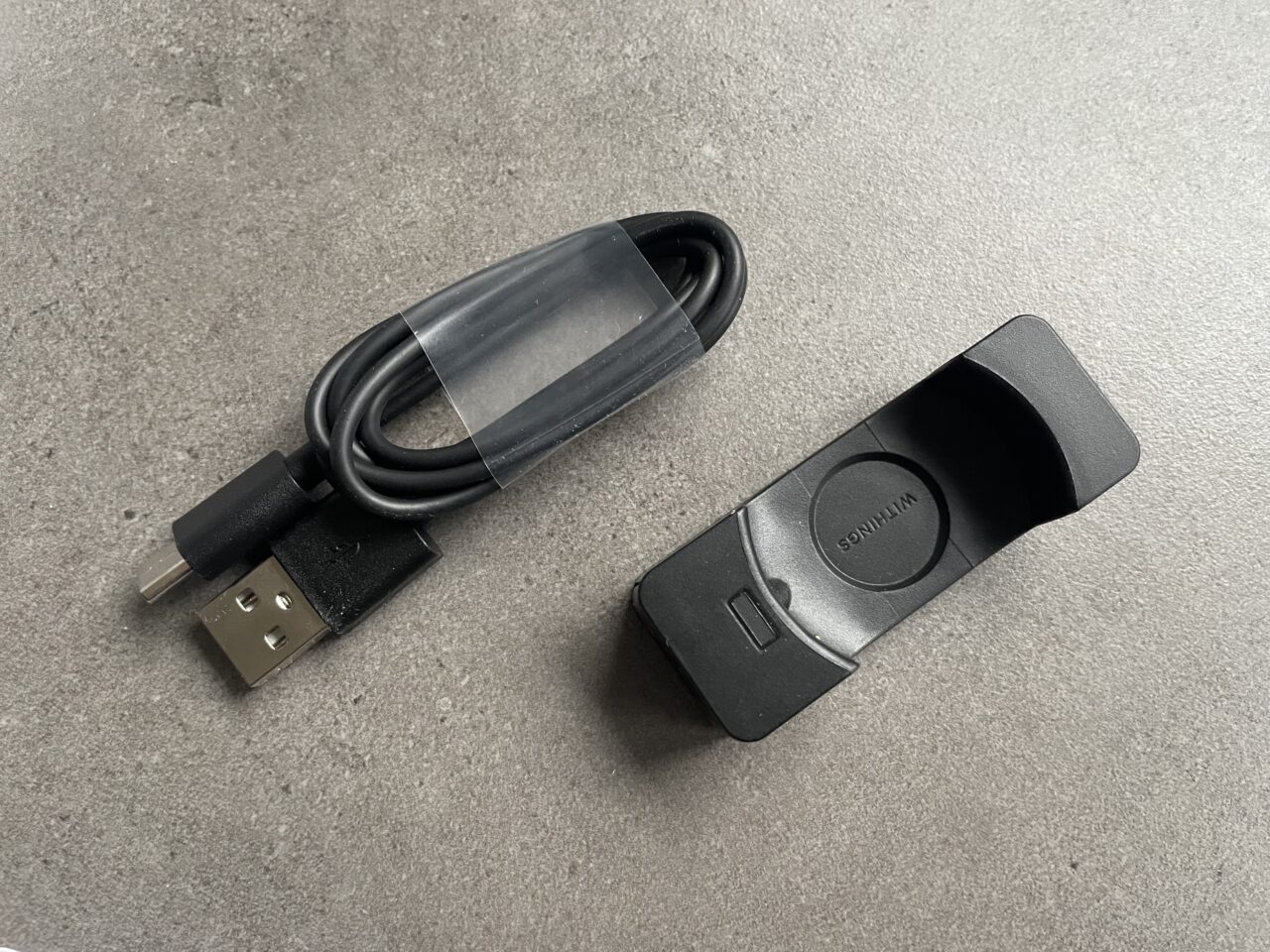 Czarny kabel USB i obudowa do elektroniki z napisem "WITTICISM" na szarym tle.