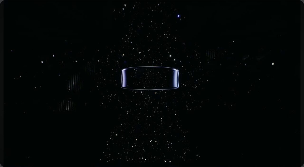 Samsung Galaxy Ring na ciemnym tle z migoczącymi punktami przypominającymi gwiazdy i centralnie umieszczonym konturem pustej, poziomej prostokątnej ramki o oświetlonych krawędziach.
