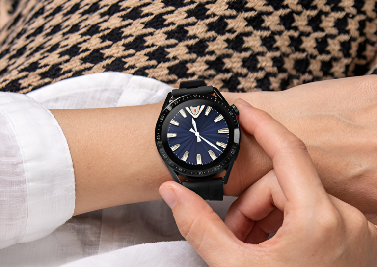 Czarny zegarek na ręku osoby na tle białej bluzki i swetra w czarno-beżowy wzór.