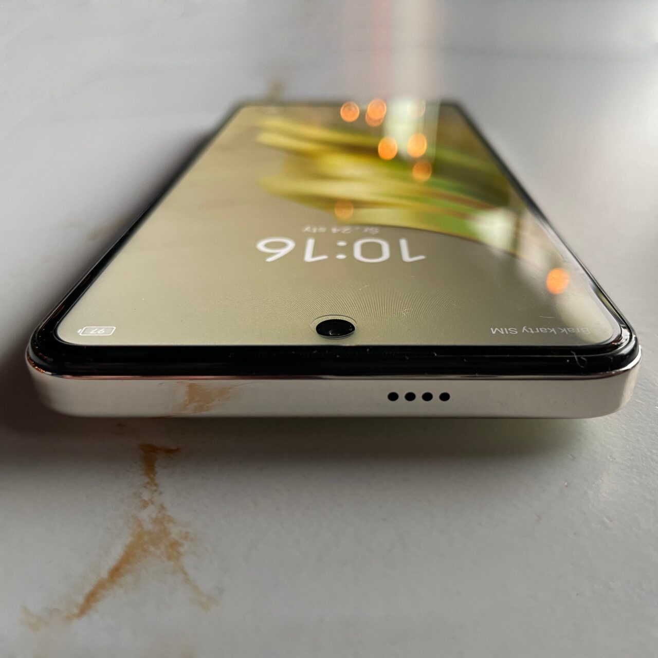 Częściowy widok czarnego smartfona tecno spark 20 pro leżącego na płaskiej powierzchni, z zarysowanymi rogami i widocznym czasem 9:01 na ekranie blokady.