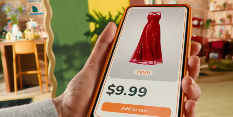 Ręka trzymająca smartfon z wyświetlonym czerwonym sukienką i ceną 9.99 dolarów na ekranie aplikacji zakupowej Temu.