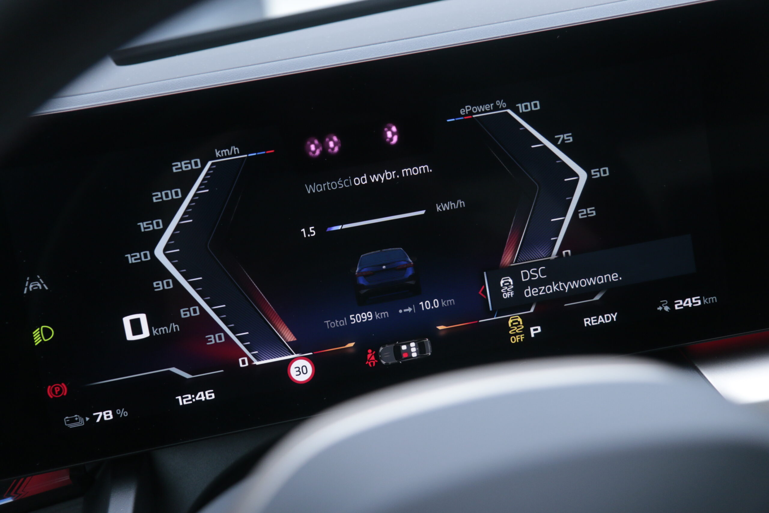 Wyświetlacz deski rozdzielczej samochodu elektrycznego BMW i5 pokazujący 0 km/h, stan naładowania baterii 78%, przejechane łącznie 5099 km, ikonę ograniczenia prędkości do 30 km/h oraz inne informacje dotyczące pojazdu.