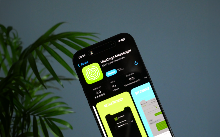 Smartfon Apple iPhone 15 Pro wyświetlający aplikację Usecrypt. Na ciemnym tle widoczna zielona roślina.