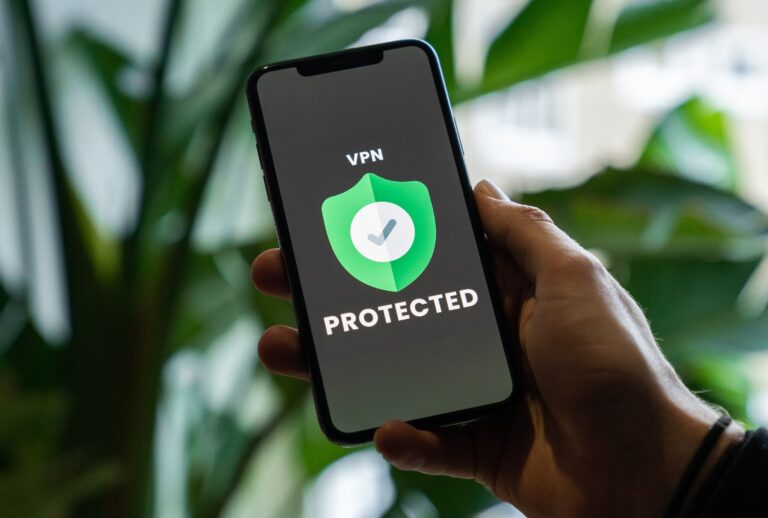 Osoba trzyma smartfon z włączoną aplikacją VPN pokazującą ekran z zieloną tarczą i napisem "PROTECTED".