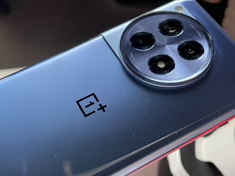 Niebieski smartfon OnePlus z poczwórnym aparatem umieszczonym w okrągłym występie na tylnej obudowie.