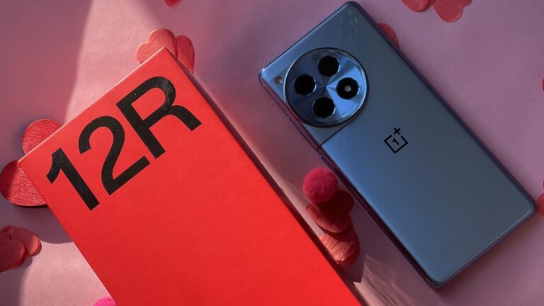 Czerwone opakowanie z napisem "12R" i szary smartfon z logiem OnePlus oraz okrągłym modułem aparatu z tyłu na różowym tle.