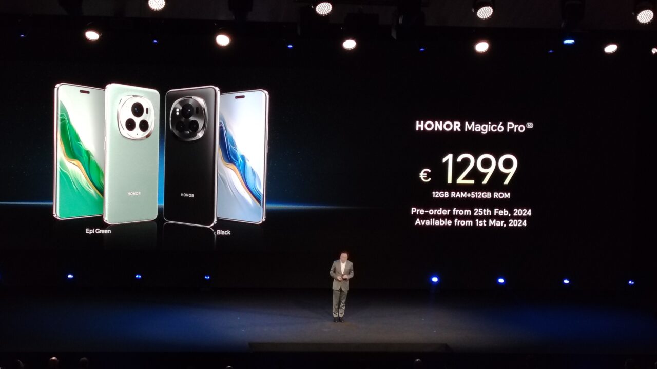 Pokaz slajdów z dwoma smartfonami HONOR Magic6 Pro w kolorach Epi Green i Black na dużym ekranie podczas prezentacji; widoczna cena 1299 euro, dane techniczne, oraz informacje o przedsprzedaży i dostępności produktu, z osobą stojącą na scenie pod ekranem.