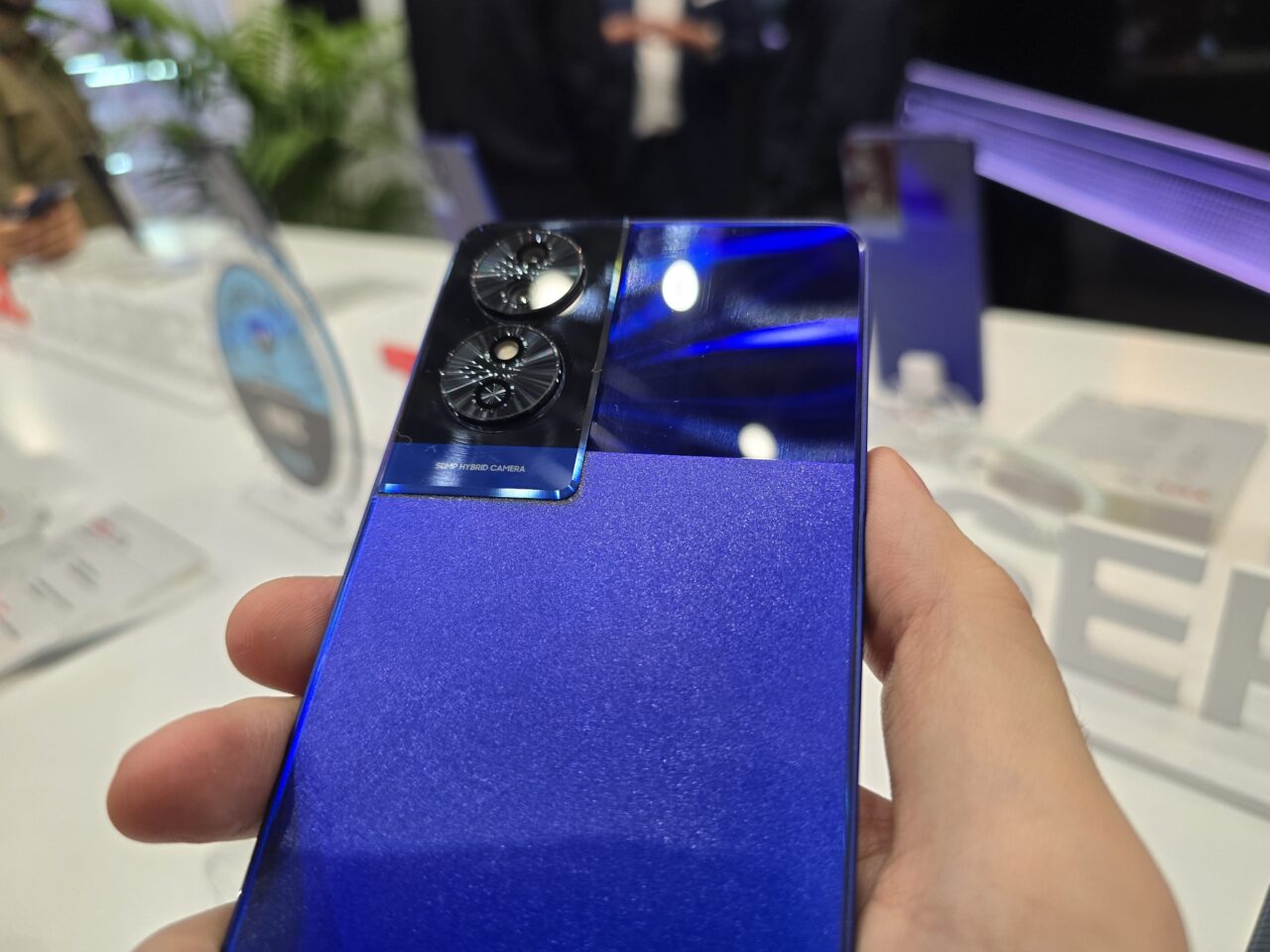 Tylna część niebieskiego smartfona trzymana w dłoni z widocznym modułem podwójnej kamery i ciekawą fakturą.