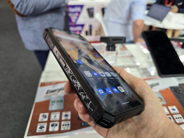 Osoba trzymająca smartfon Energizer Hard Case P28K z wyświetlonym ekranem głównym, pokazującym ikony aplikacji, w sklepie z elektroniką.