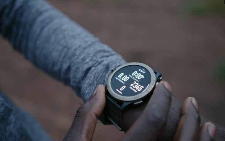 Osoba sprawdzająca czas i przebyty dystans na cyfrowym zegarku sportowym na nadgarstku.