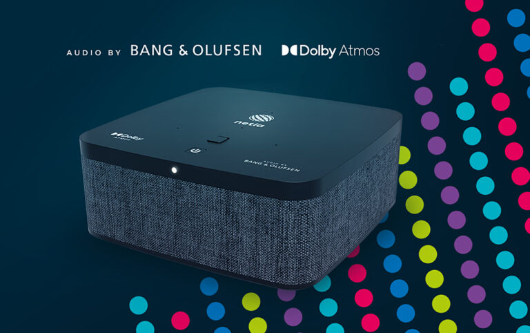 Dekoder Netia Soundbox 4K z górnym panelem dotykowym, oznaczony logiem Bang & Olufsen oraz Dolby Atmos, na ciemnoniebieskim tle z kolorowymi kropkami.