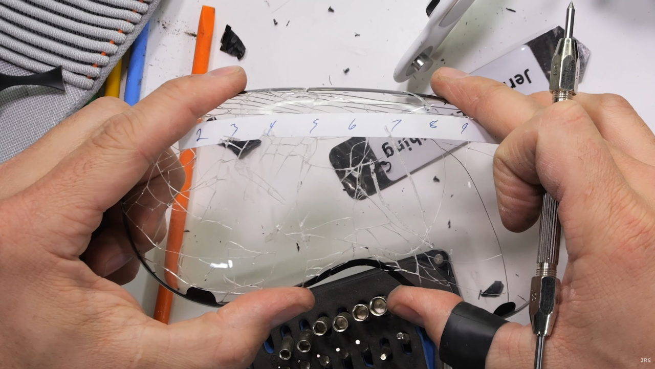 Ręce naprawiające rozbite szkło smartfona z narzędziami na biurku.