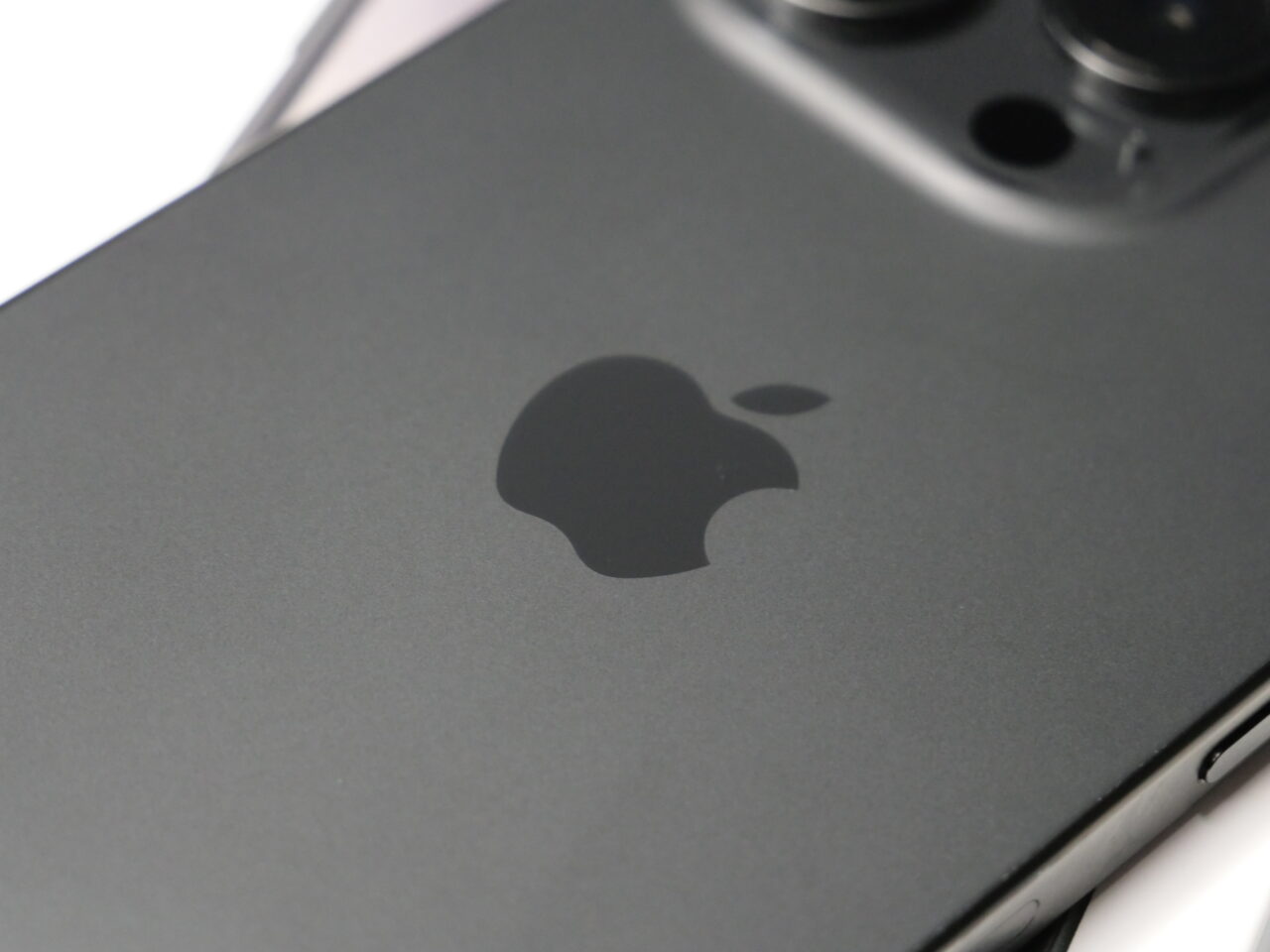 Część tylna czarnego smartfona z widocznym logo Apple i fragmentem systemu kamer.