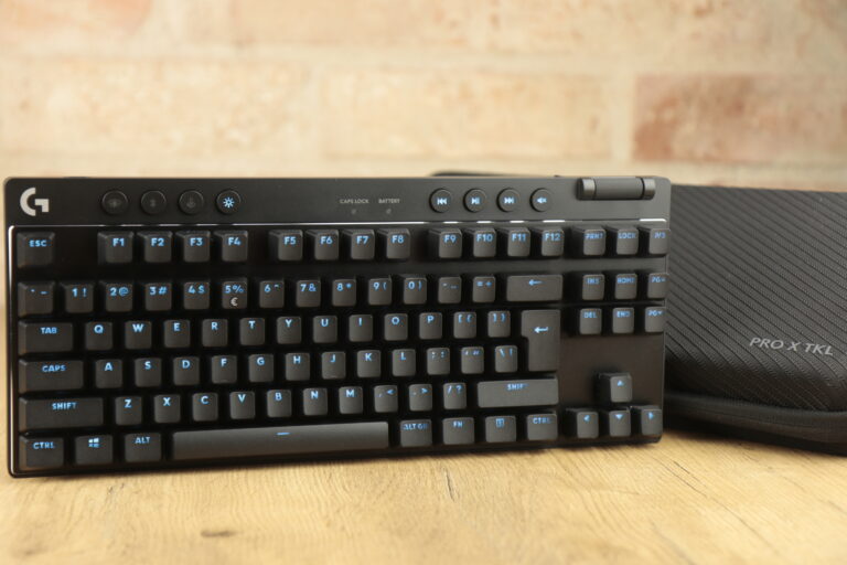 Czarna, mechaniczna klawiatura gamingowa Logitech G Pro x tkl lightspeed z podświetlanymi klawiszami i dedykowanymi przyciskami multimedialnymi, leżąca na biurku obok podkładki pod nadgarstek z napisem "PRO X TKL".