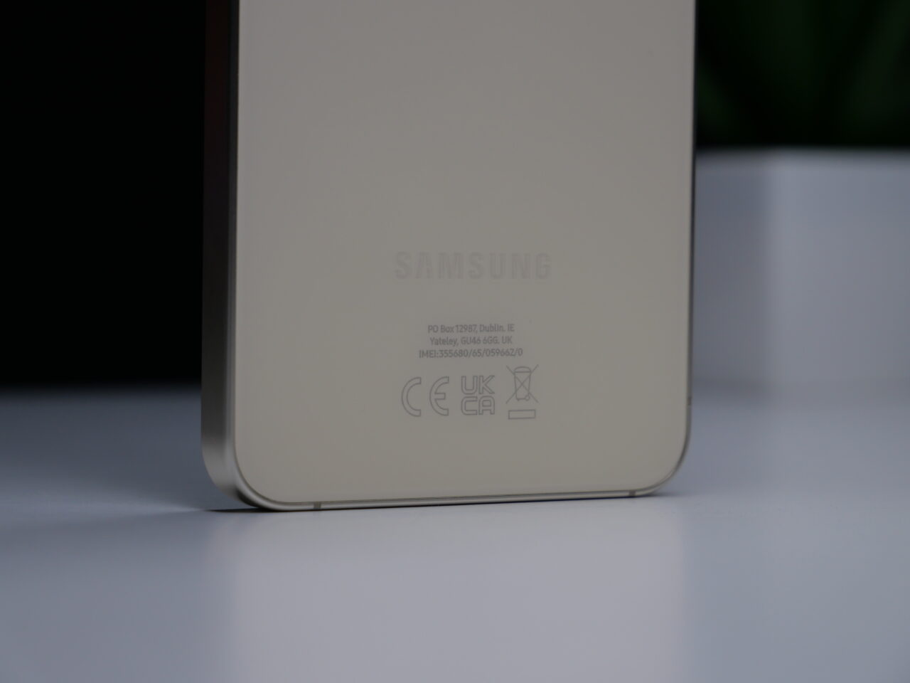 Zbliżenie na tylną część białego urządzenia marki Samsung z widocznymi oznaczeniami modelu i certyfikatami.