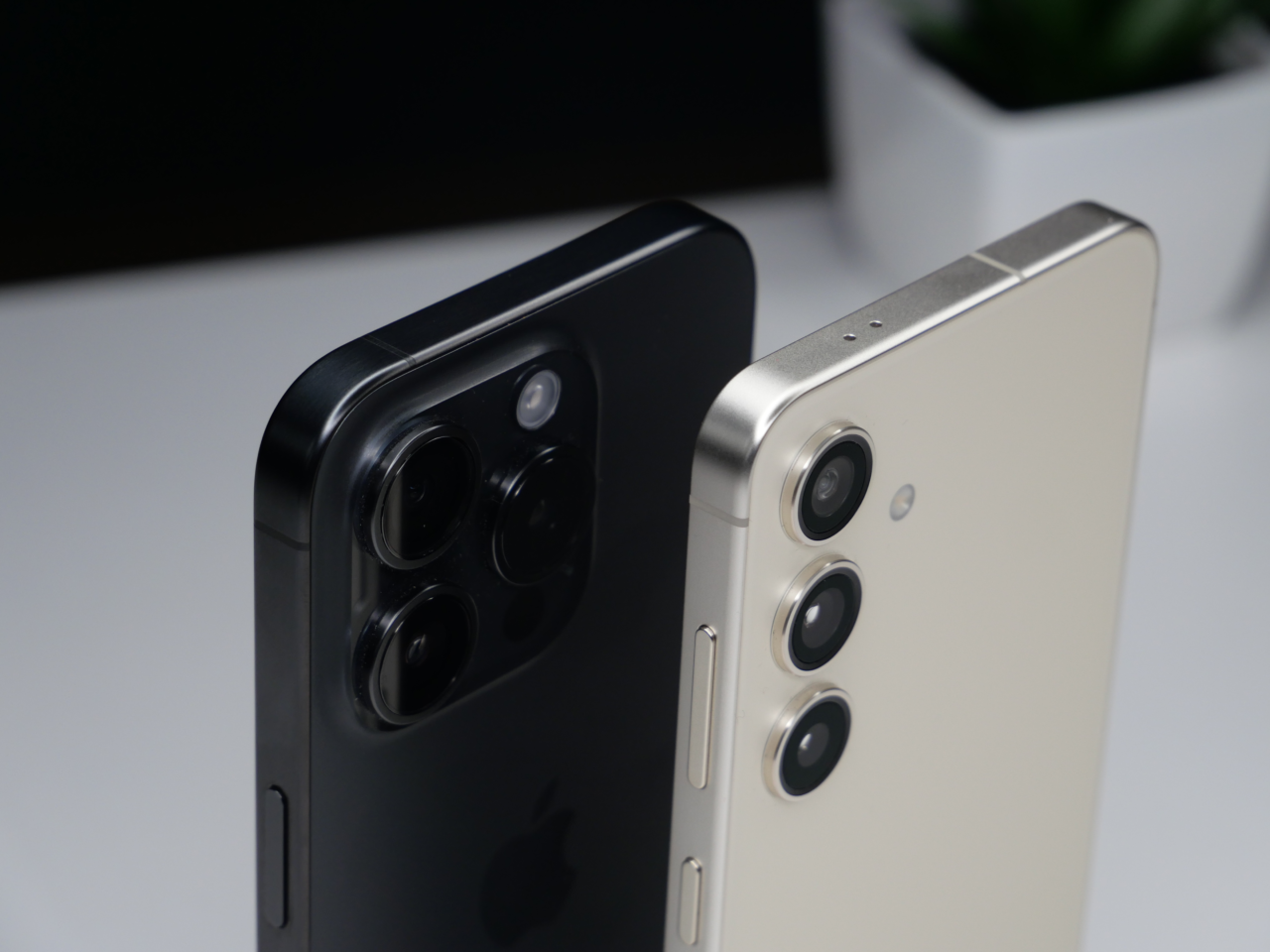 Dwa smartfony ustawione tyłem, jeden czarny, a drugi biały, pokazujące układy potrójnych aparatów fotograficznych.