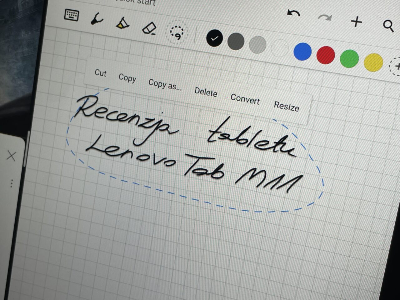 Ręcznie pisany tekst "Recenzja tabletu Lenovo Tab M8" otoczony niebieską, przerywaną linią na ekranie tabletu z otwartym programem do rysowania.