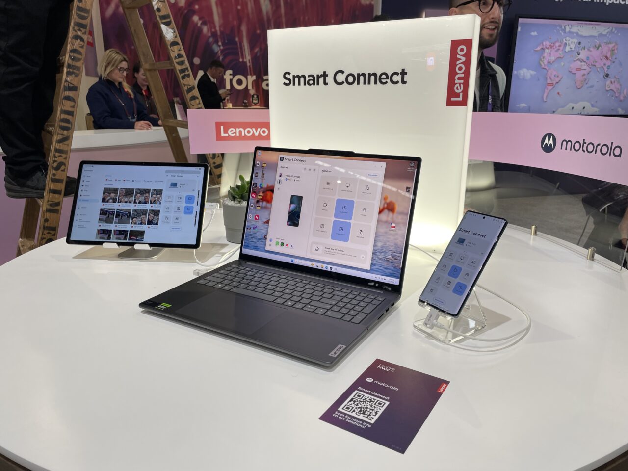 Stoisko Lenovo z laptopem, monitorem i smartfonem prezentującymi technologię "Smart Connect".