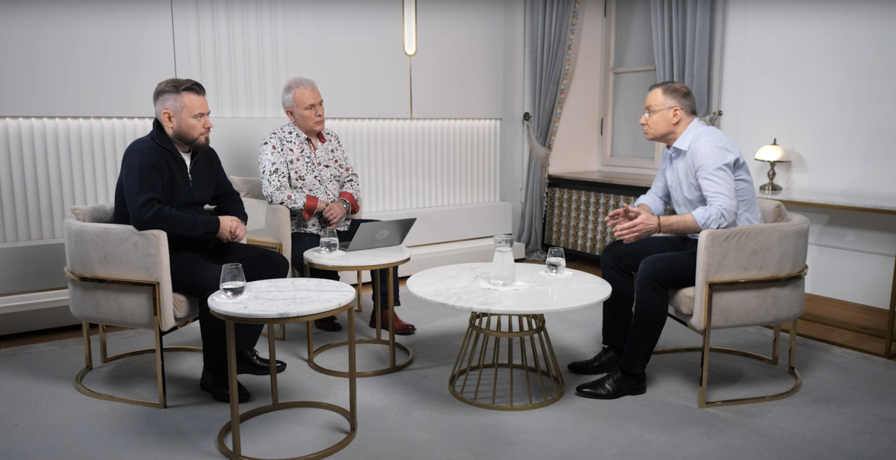 Zdjęcie z Kanału Zero i rozmowy z Andrzejem Dudą. Trzej mężczyźni siedzą w elegancko urządzonym pokoju i prowadzą rozmowę; dwoje z nich siedzi razem naprzeciwko trzeciego, przy stolikach kawowych.
