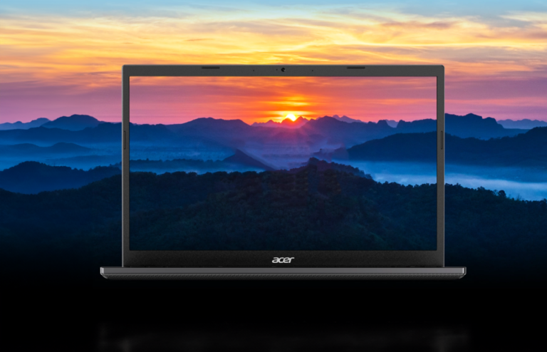 Laptop Acer przedstawiający zdjęcie wschodu słońca nad górskim łańcuchem i mglistą doliną.