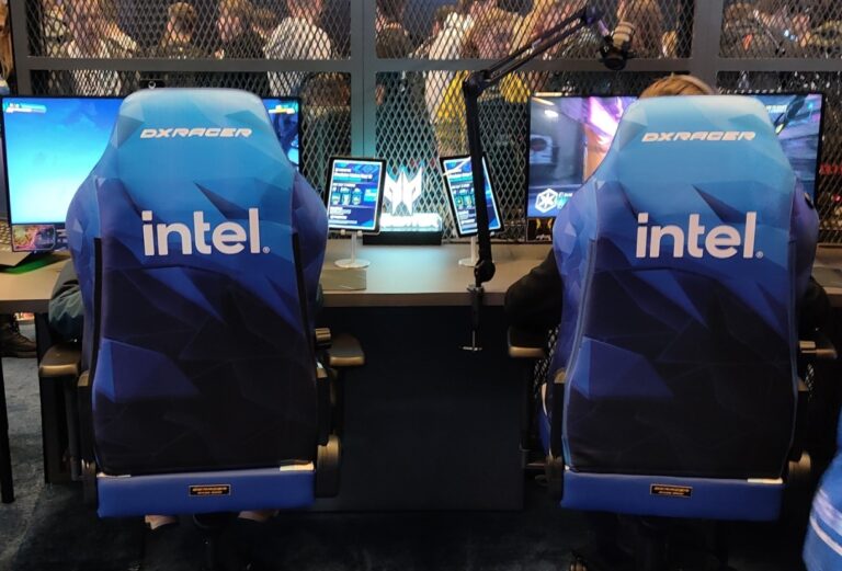 Strefa gamingowa z dwoma fotelami marki DXRacer z logo Intel na IEM Katowice 2024,, przed nimi monitory komputerowe i mikrofony.