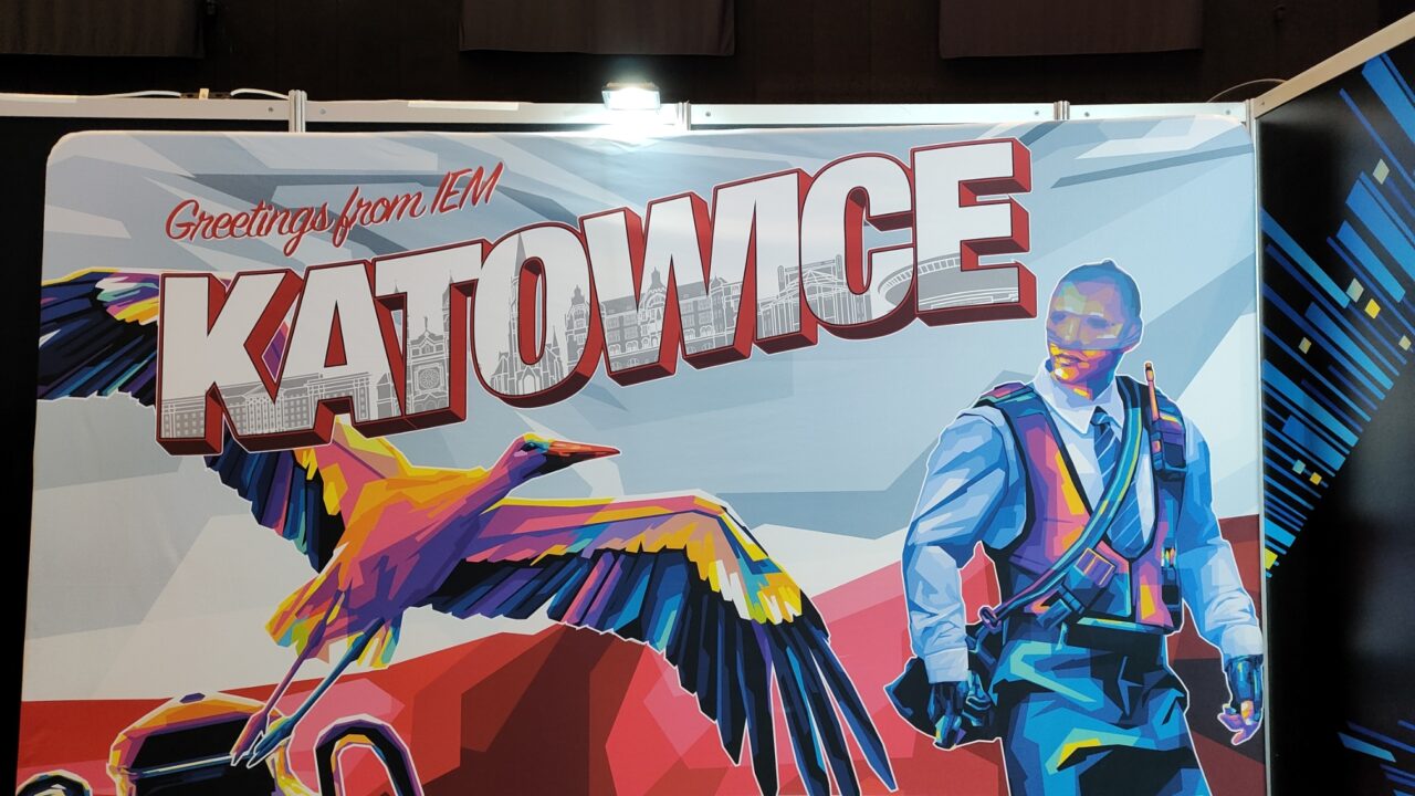 Banner com a inscrição "Saudações do IEM Katowice" com uma representação gráfica colorida e estilizada de um pássaro e um homem com um rádio.