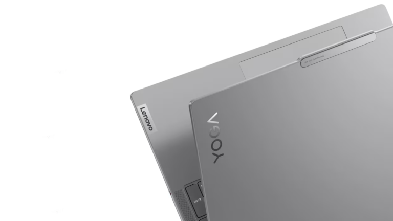 Srebrny laptop marki Lenovo, częściowo otwarty, z widocznym logo na pokrywie, umieszczonym na jasnym tle.