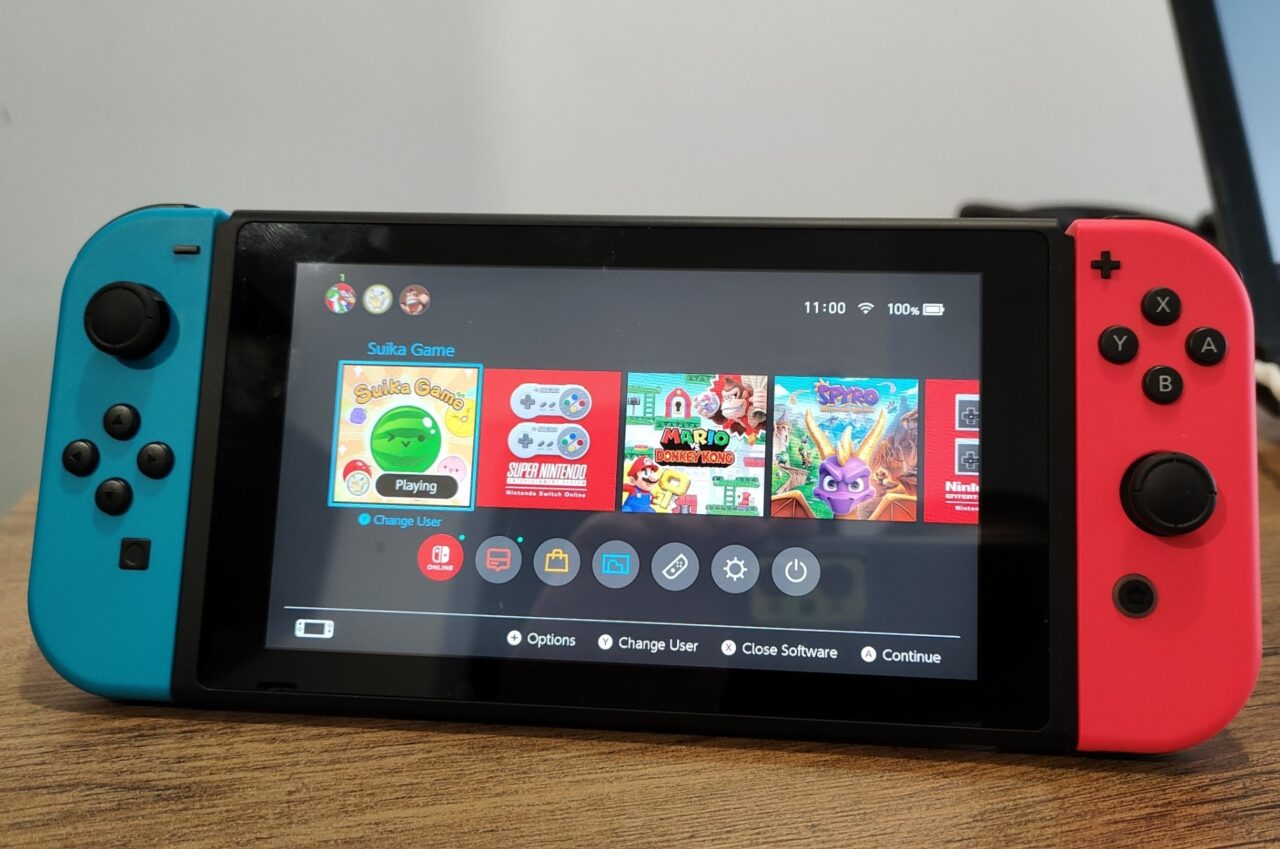 Nintendo Switch na stole, przedmiot sporu Nintendo vs Yuzu pokazujący ekran główny z grami i bocznymi kontrolerami Joy-Con w kolorach niebieskim i czerwonym.