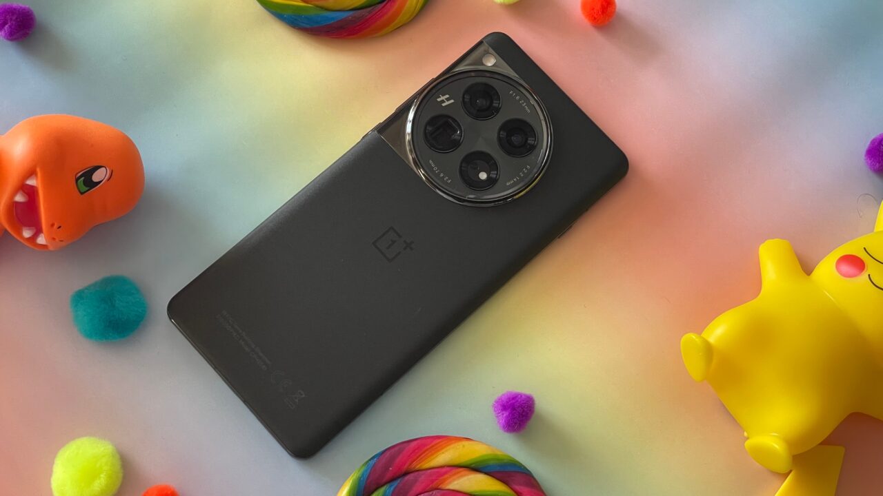 Um smartphone OnePlus preto com uma câmera de lente tripla colocada sobre um fundo colorido com bolas e brinquedos coloridos.