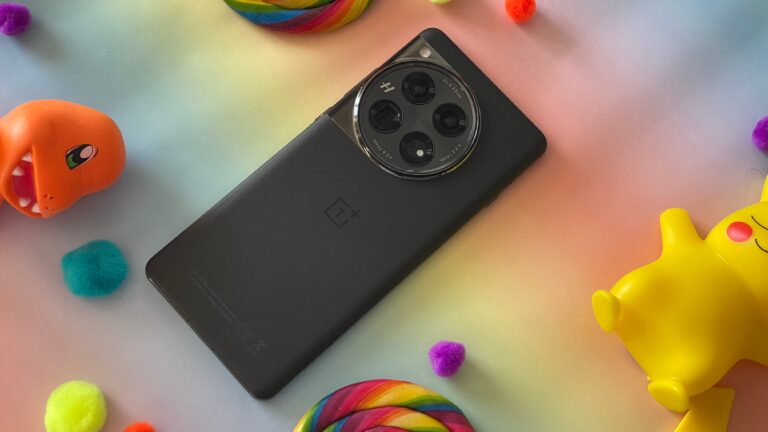Czarny smartfon OnePlus z aparatem z trzema obiektywami umieszczony na kolorowym tle z kolorowymi kulkami i zabawkami.