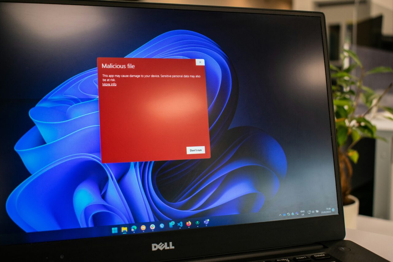 Monitor komputera Dell wyświetlający ostrzeżenie o złośliwym pliku na tle tapety systemu Windows.