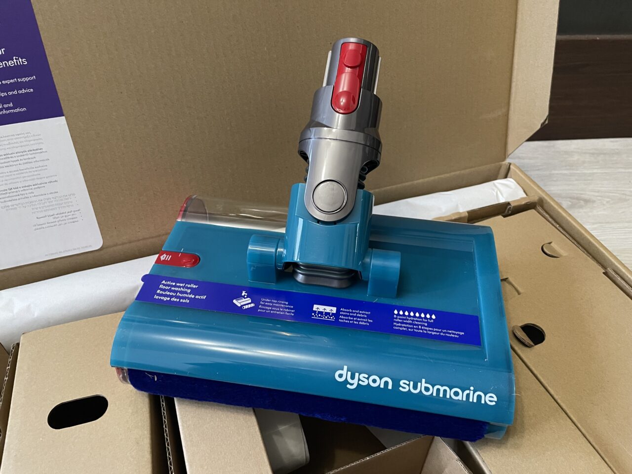 Niebieska szczotka elektryczna do odkurzacza marki Dyson oznaczona jako "submarine", wyjęta z kartonowego opakowania.