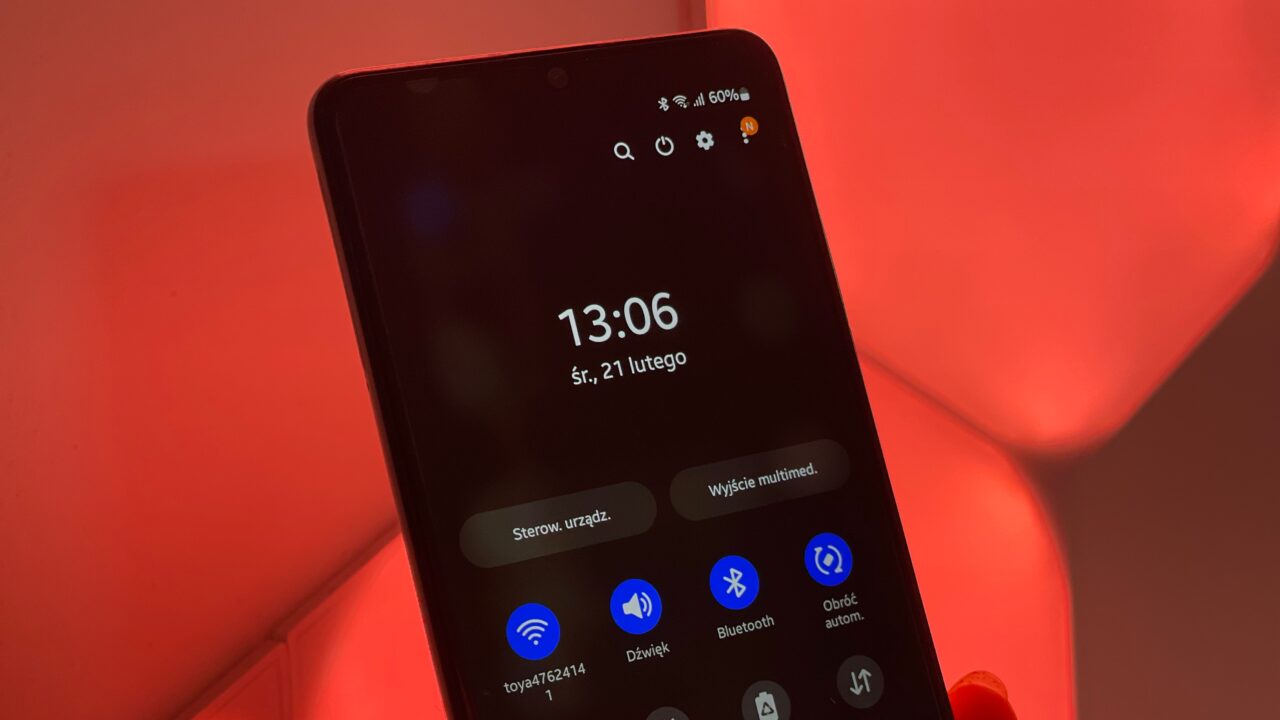 Jak zresetować telefon Samsung. Komórka wyświetlająca ekran blokady z godziną 13:06 i datą środa, 21 lutego, na tle oświetlonym na czerwono.