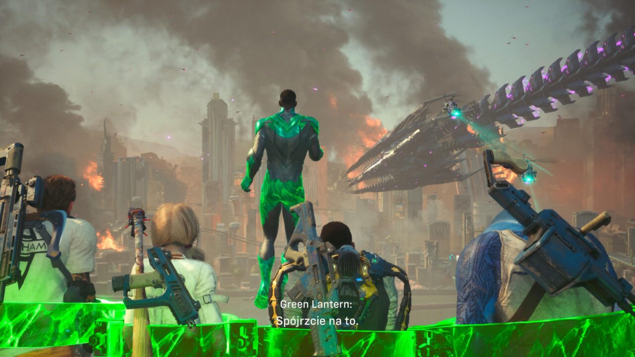 Scena z gry komputerowej przedstawiająca bohaterów w futurystycznym, zniszczonym mieście, patrzących na unoszącego się w powietrzu postać Green Lantern, który stoi na zielonej, energetycznej barierze. W tle widoczny olbrzymi statek przypominający robaka z fioletowymi akcentami dzierżącego zieloną energię, a nad miastem unosi się dym. Na obrazie widnieje napis "Green Lantern: Spójrzcie na to".