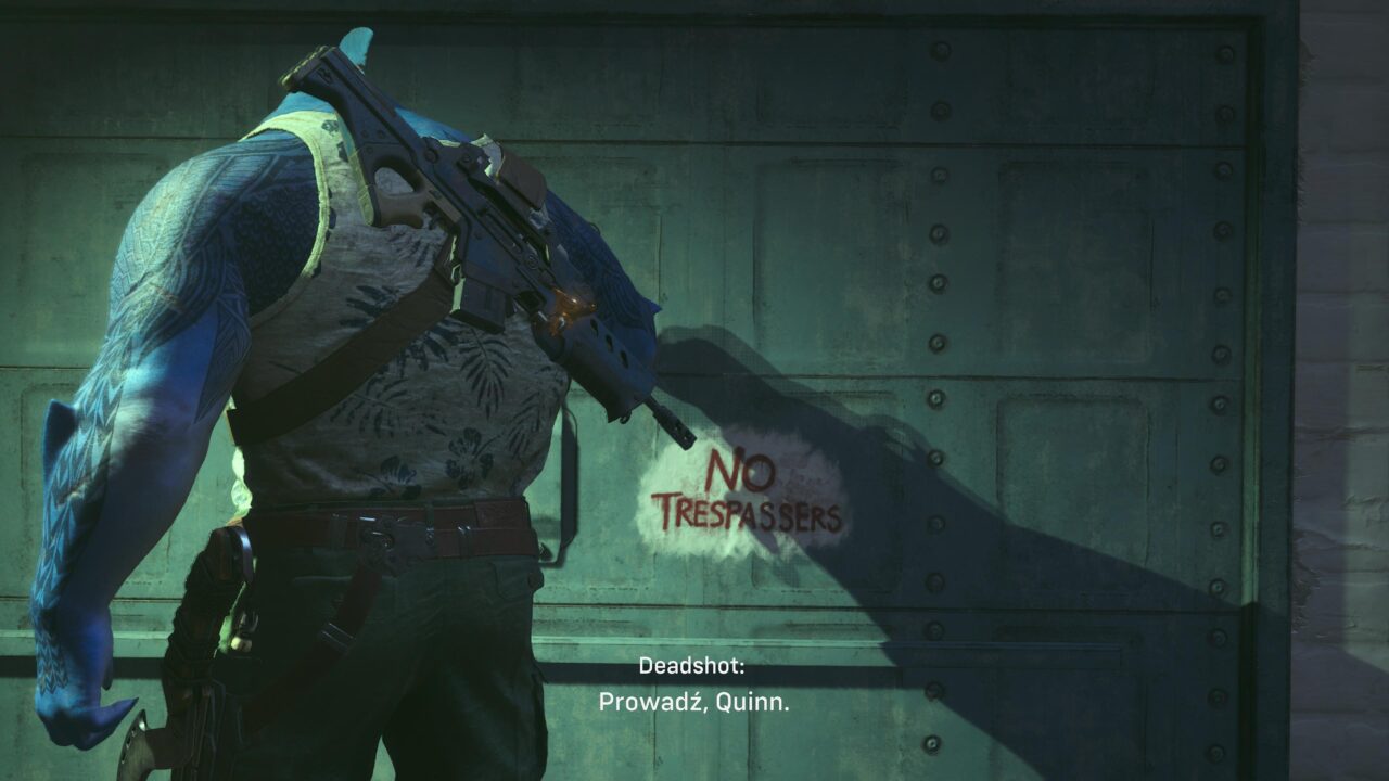 Postać o niebieskiej skórze i tatuażach, trzymająca broń, stoi obok muru z napisem "NO TRESPASSERS". Na dole ekranu widnieje tekst "Deadshot: Prowadź, Quinn."