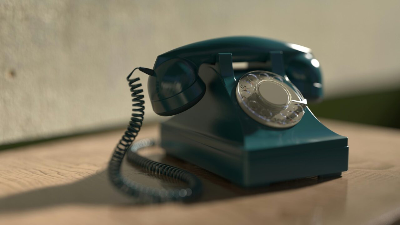 Niebieski telefon z tarczą numeracyjną umieszczony na drewnianym blacie.
