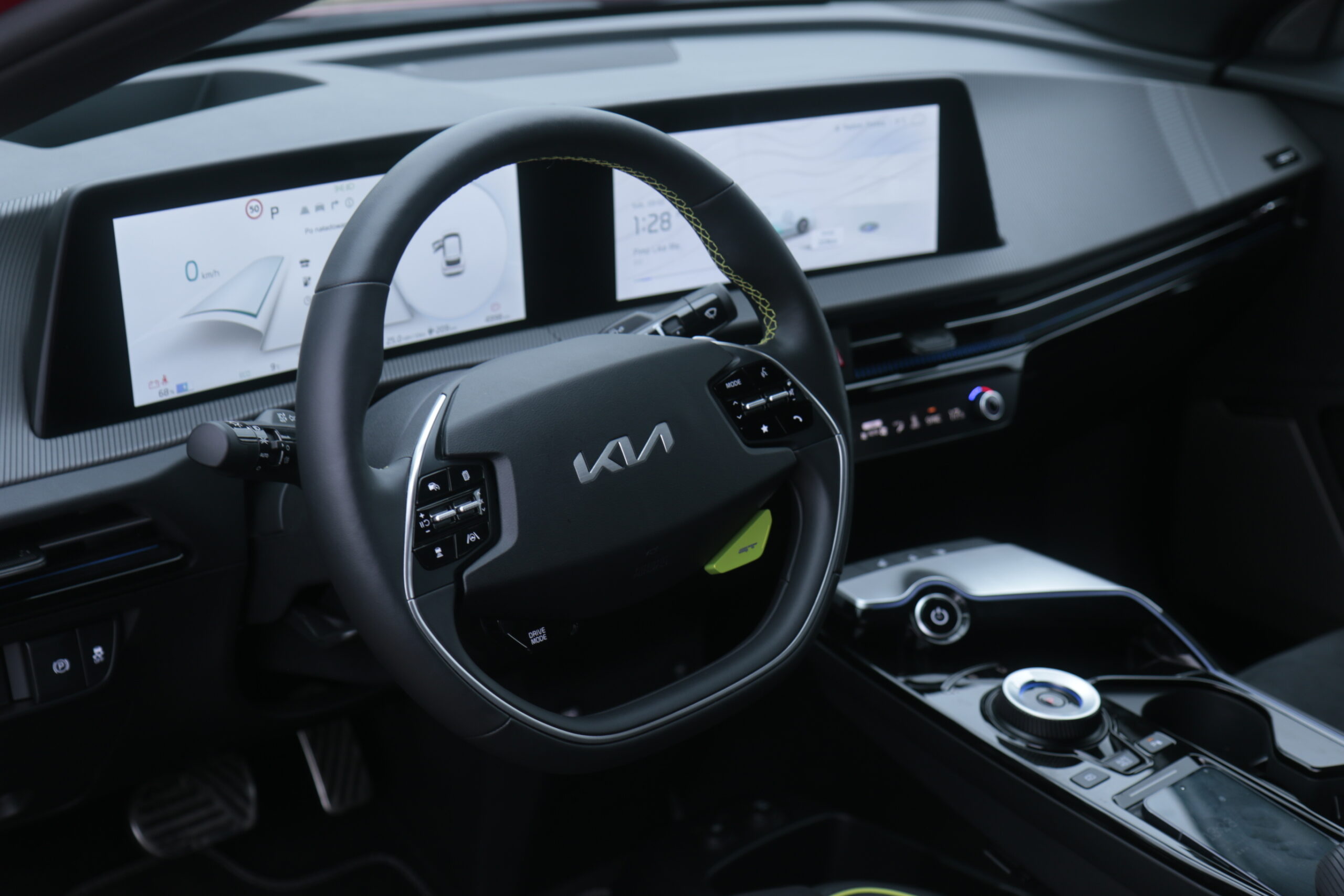 Wnętrze samochodu marki Kia EV6 GT z widocznym kierownicą i dwoma cyfrowymi wyświetlaczami deski rozdzielczej.