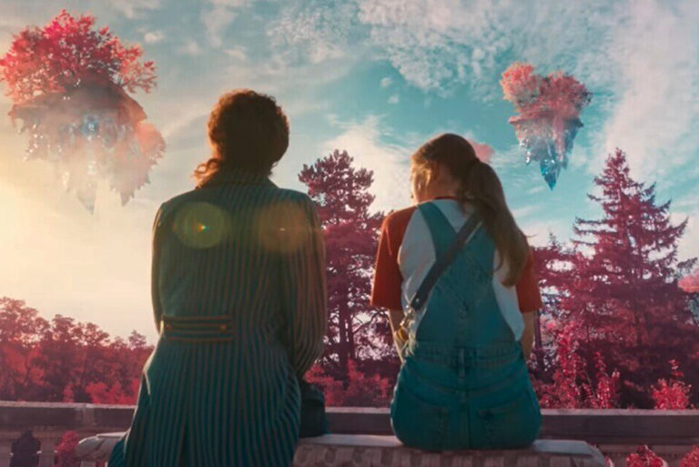 Kadr z filmu Akademia Pana Kleksa. Dwie osoby stoją plecami do widza, obserwując niebiańskie, unoszące się wyspy o różowej roślinności nad lasem w świetle zachodzącego słońca.