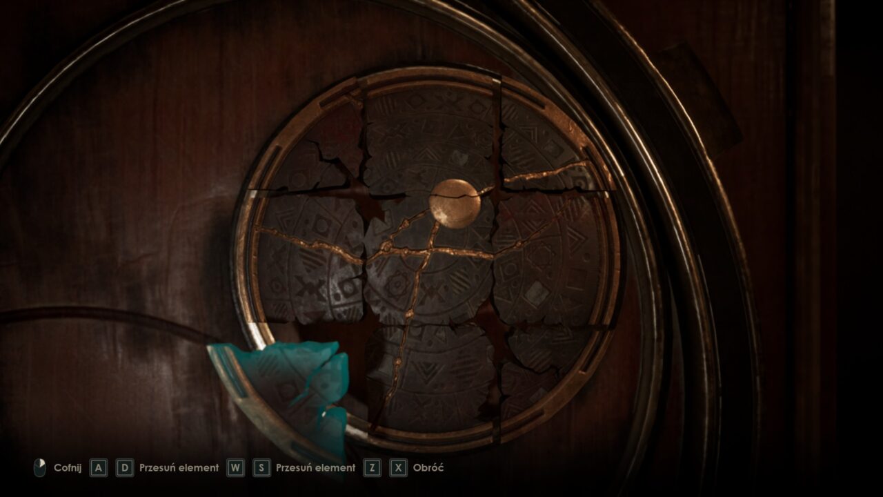 Obraz przedstawia złamaną kamienną tarczę z symbolem plecionki, ułożoną w drewnianej obudowie, ze sterowaniem gry na pierwszym planie.